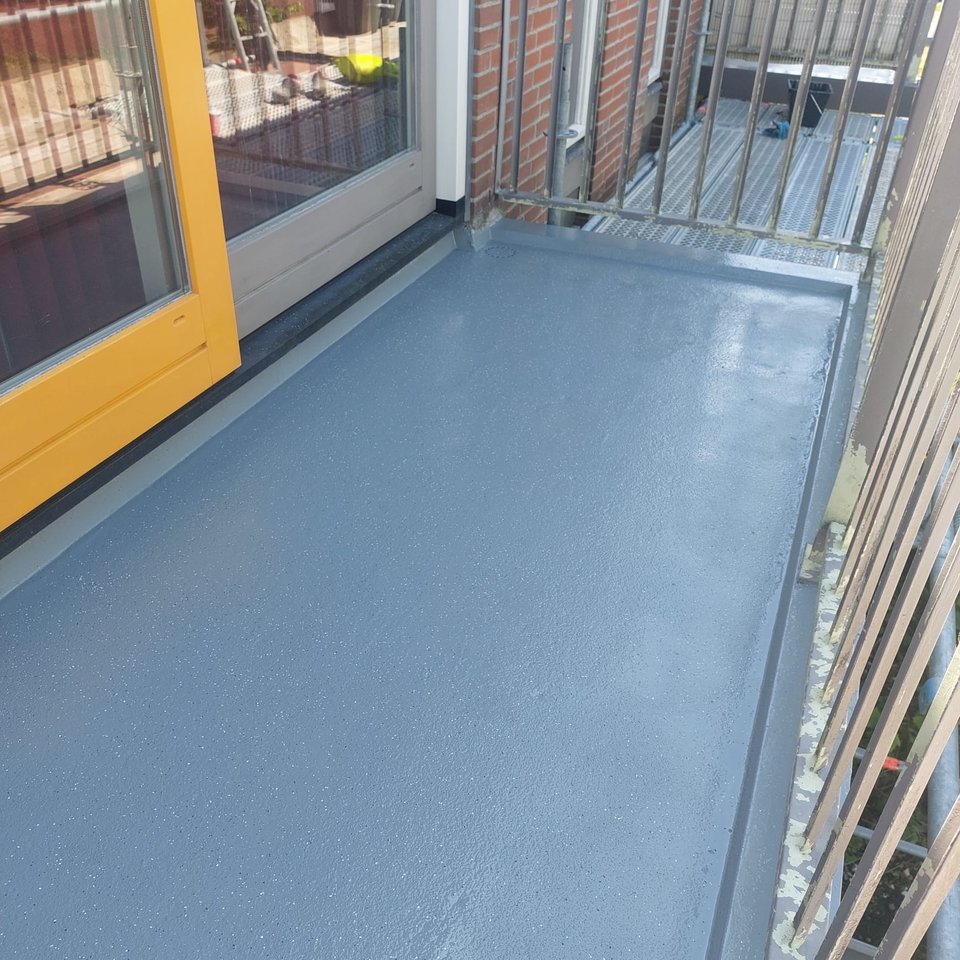 Gerenoveerd balkon met strakke grijze coating